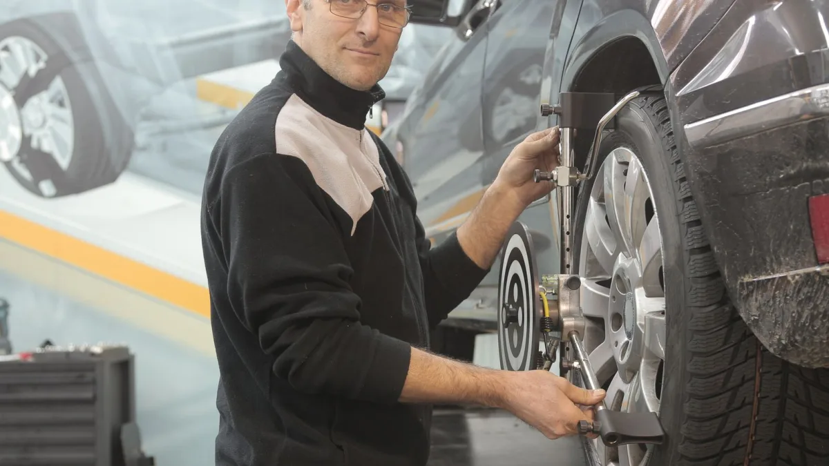 Technician setting up an ADAS calibration target board in front of a parked car