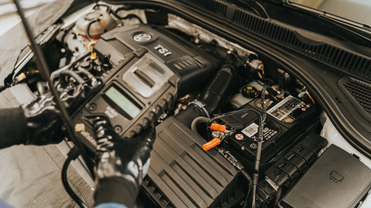Technician reconnecting a car battery terminal under the hood