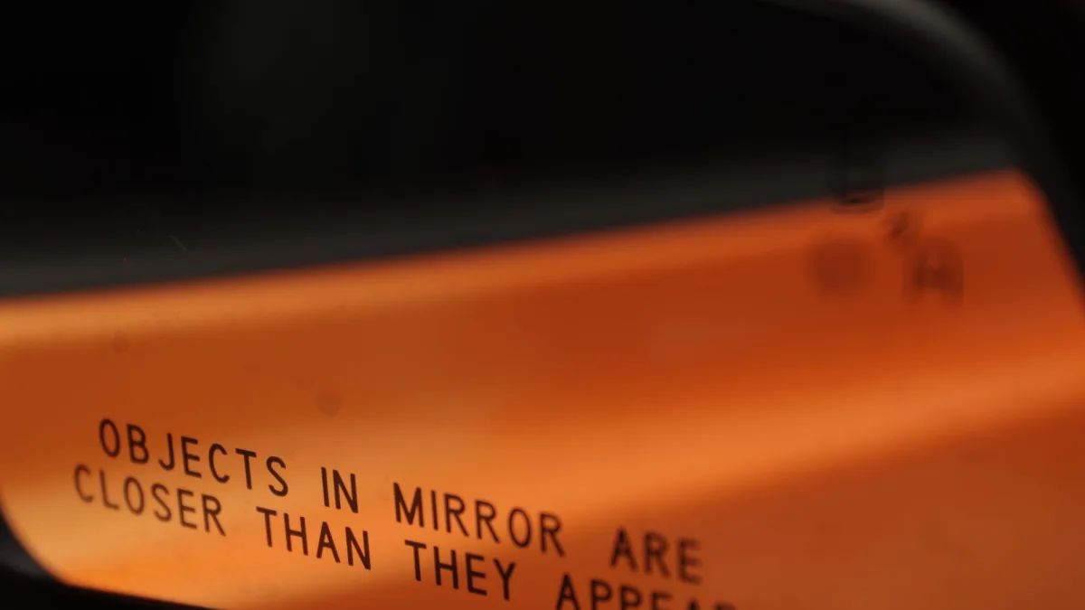 Amber blind spot warning triangle illuminated in a side mirror glass