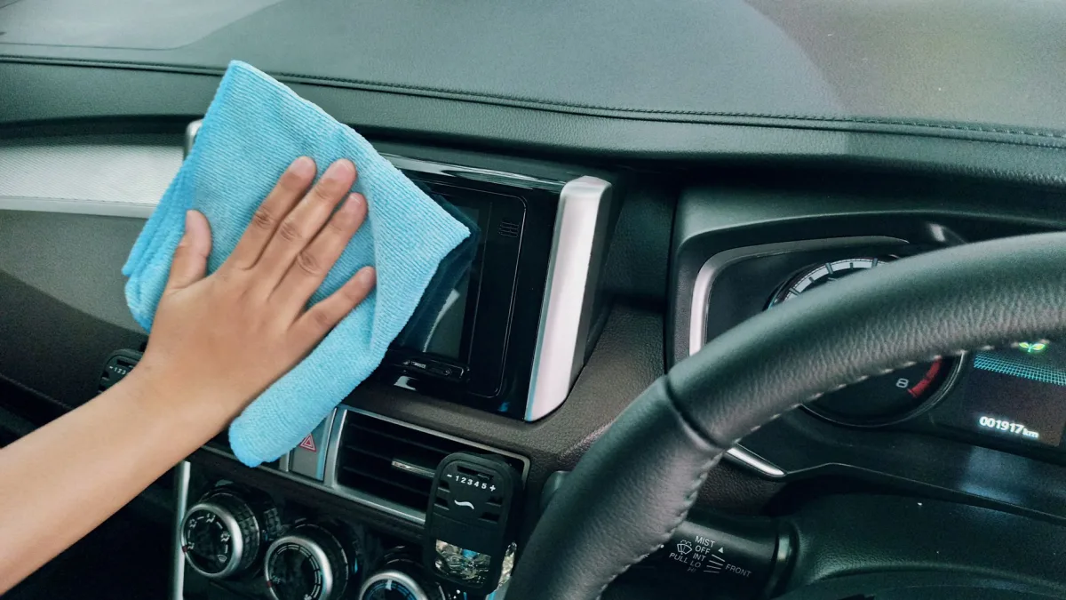 Hand using a microfiber cloth to wipe the rear corner of a car bumper