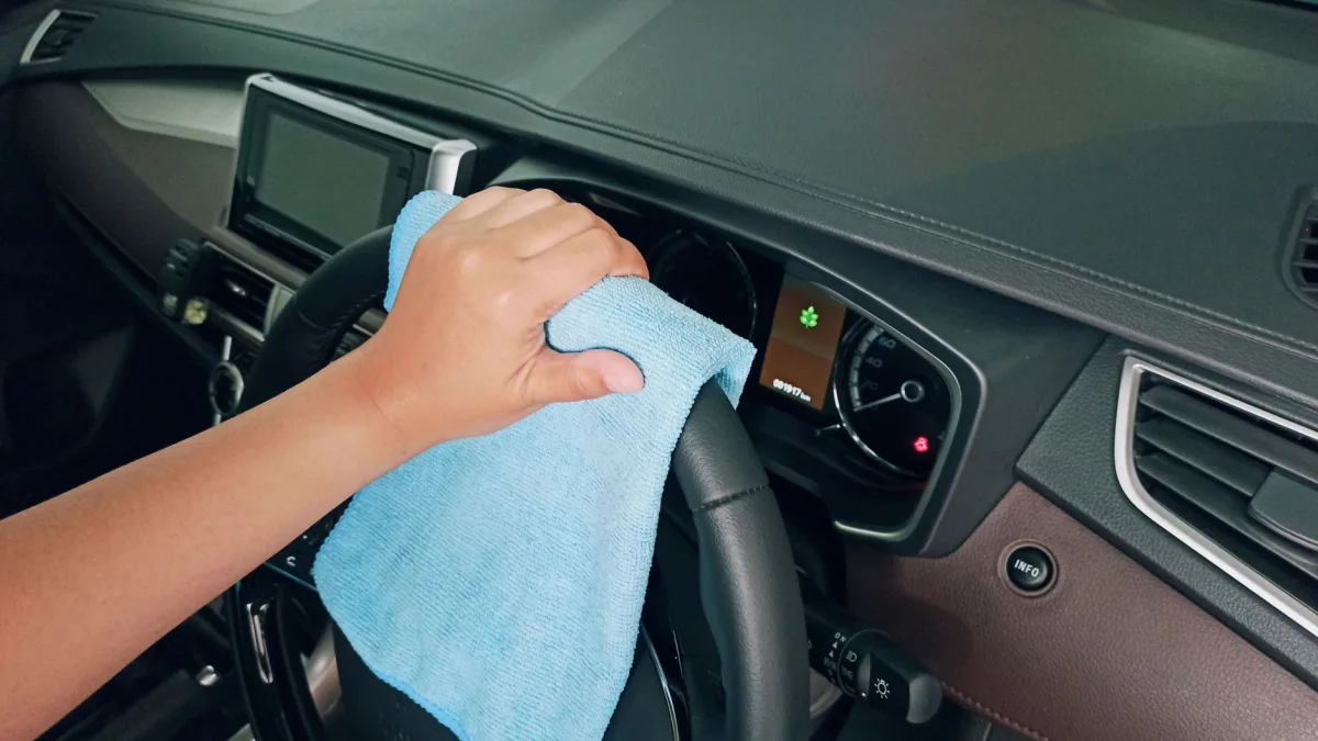 A hand using a microfiber cloth to wipe a round bumper sensor