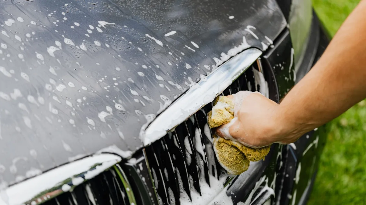 Hand wiping road grime from a lower grille area near a radar sensor
