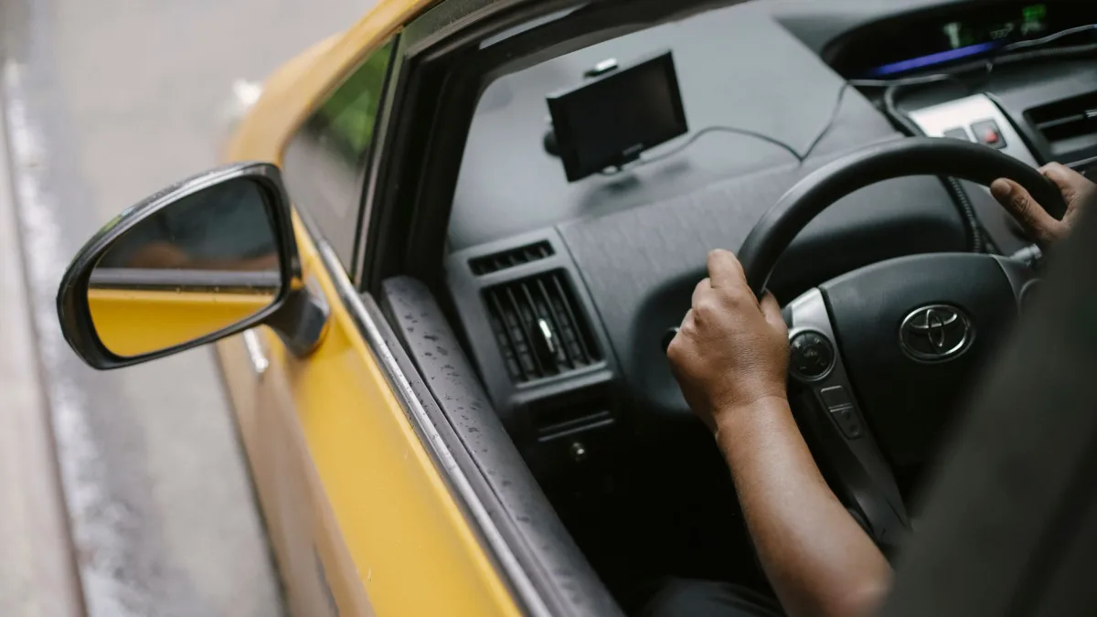 Amber blind spot warning icon glowing in a side mirror as a driver holds the wheel