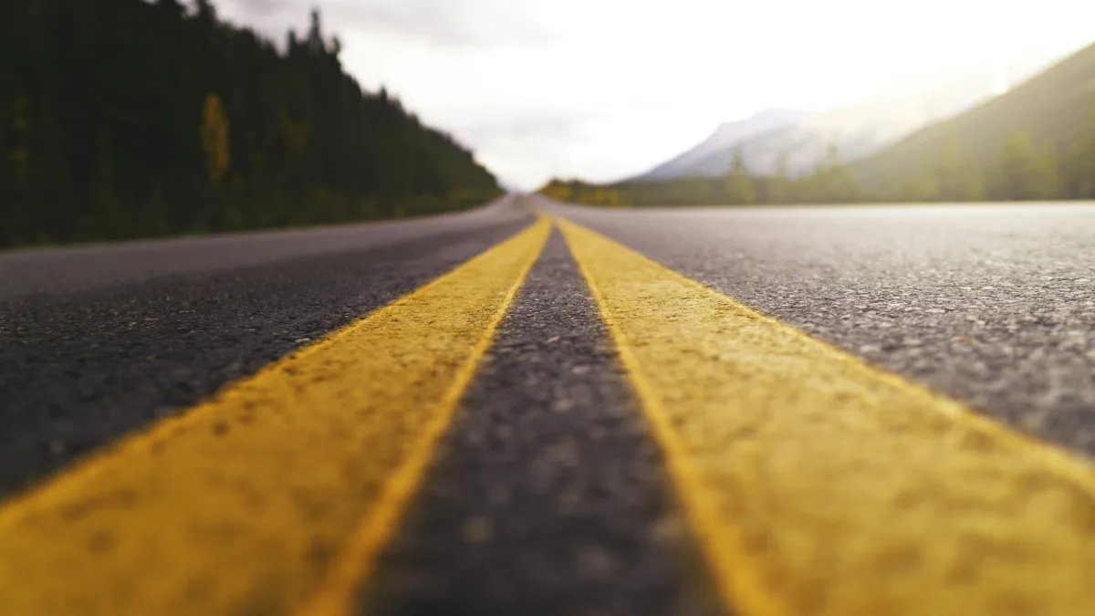 Worn and faded white lane line barely visible on aged highway pavement