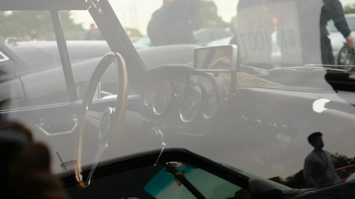 Technician working near a windshield-mounted forward camera housing during service