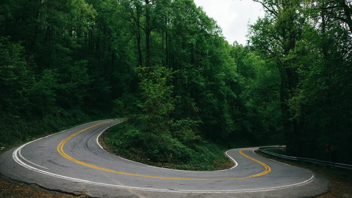 A tight two-lane mountain road curving sharply between guardrails
