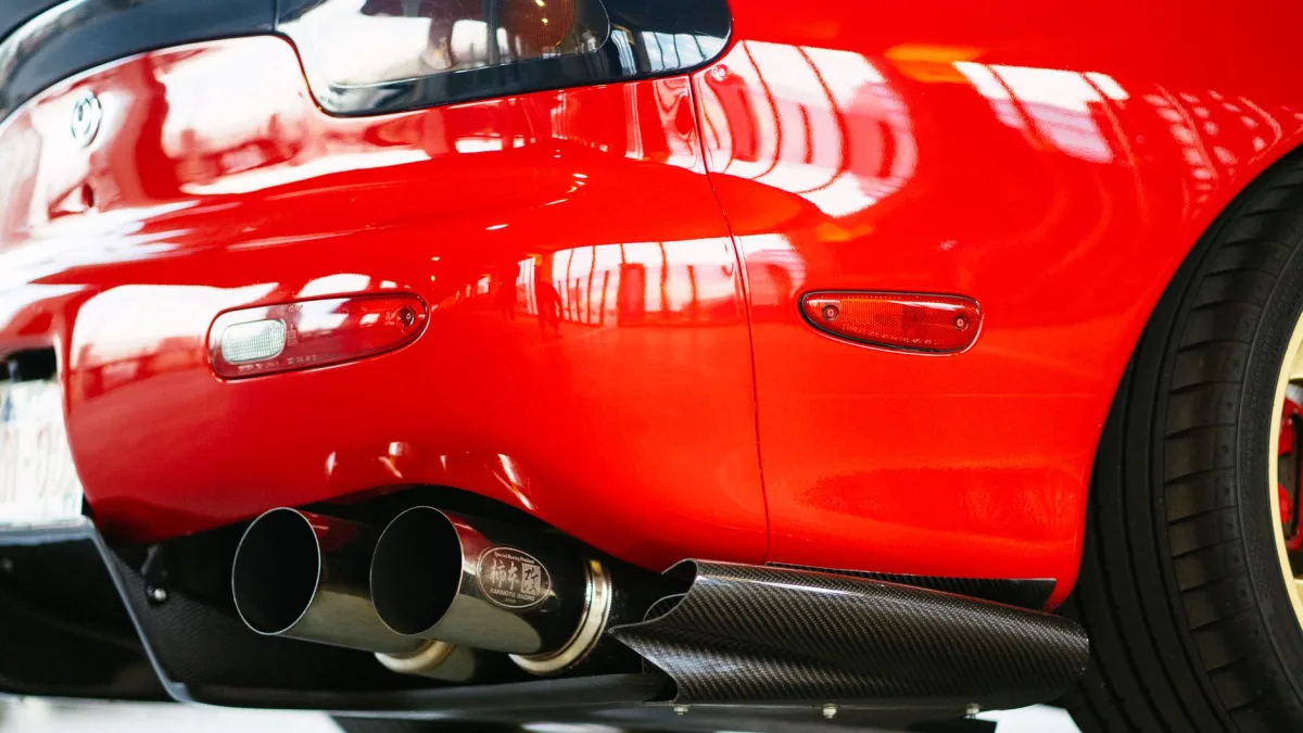 Hand wiping the rear bumper corner of a Mazda where the RVM radar sits