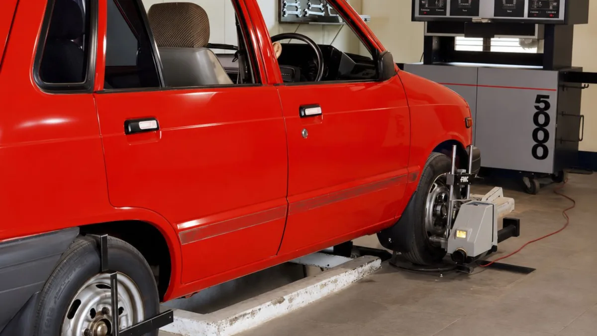 Technician positioning a printed calibration target board in front of a parked vehicle