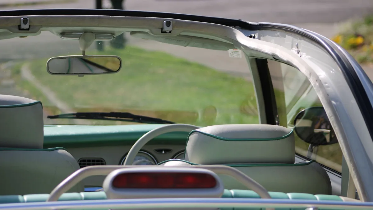 Interior view of a windshield showing a dark tint band near the mirror housing