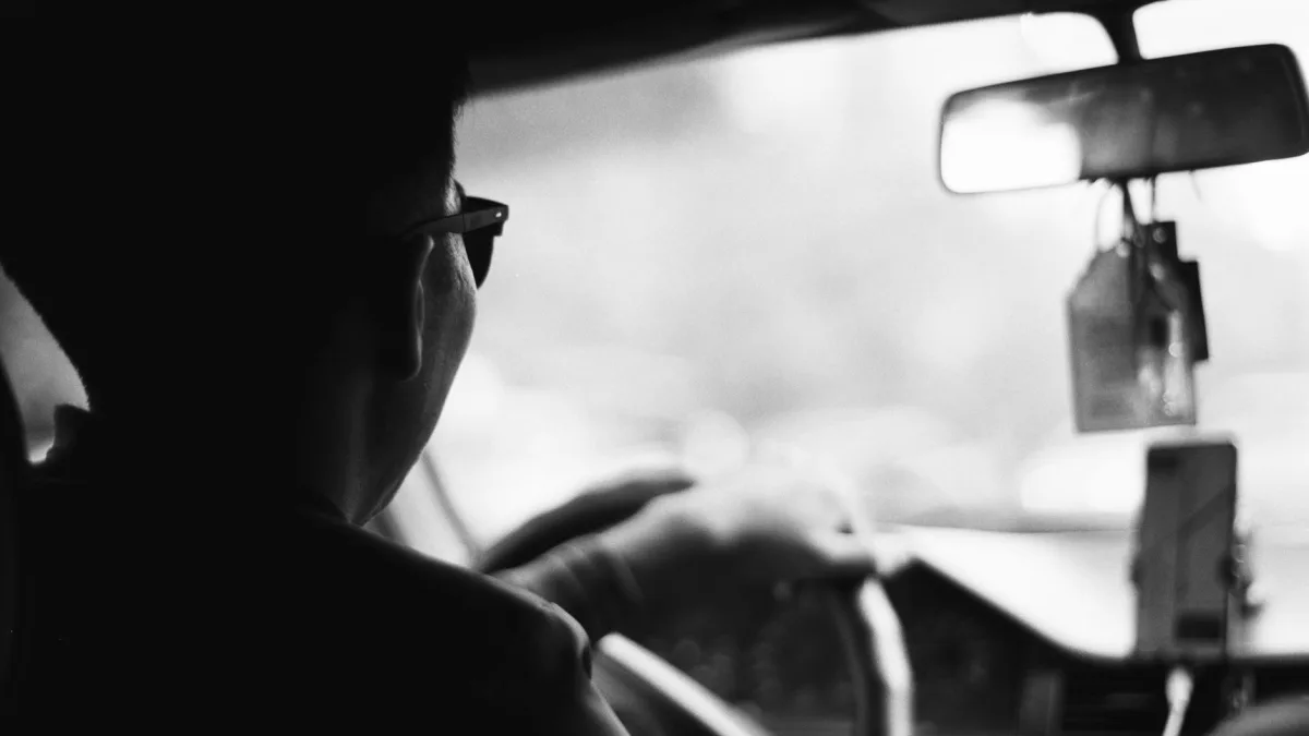Forward-facing ADAS camera housing mounted behind a used car rearview mirror