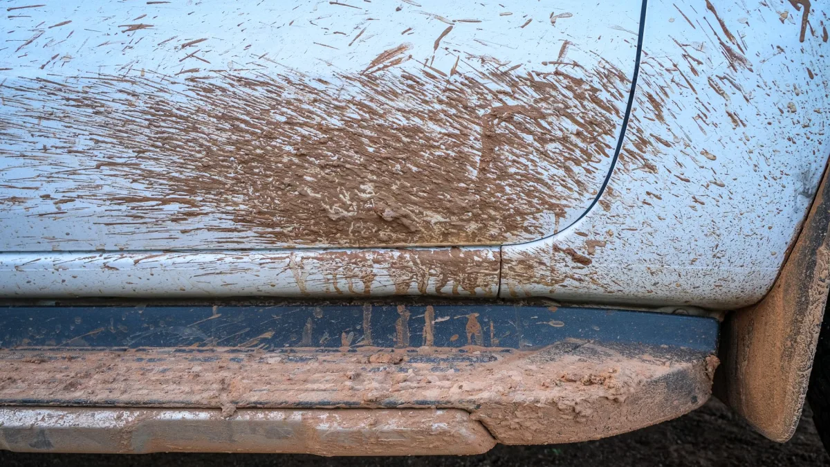 Rear bumper corner caked with dried mud over a hidden sensor