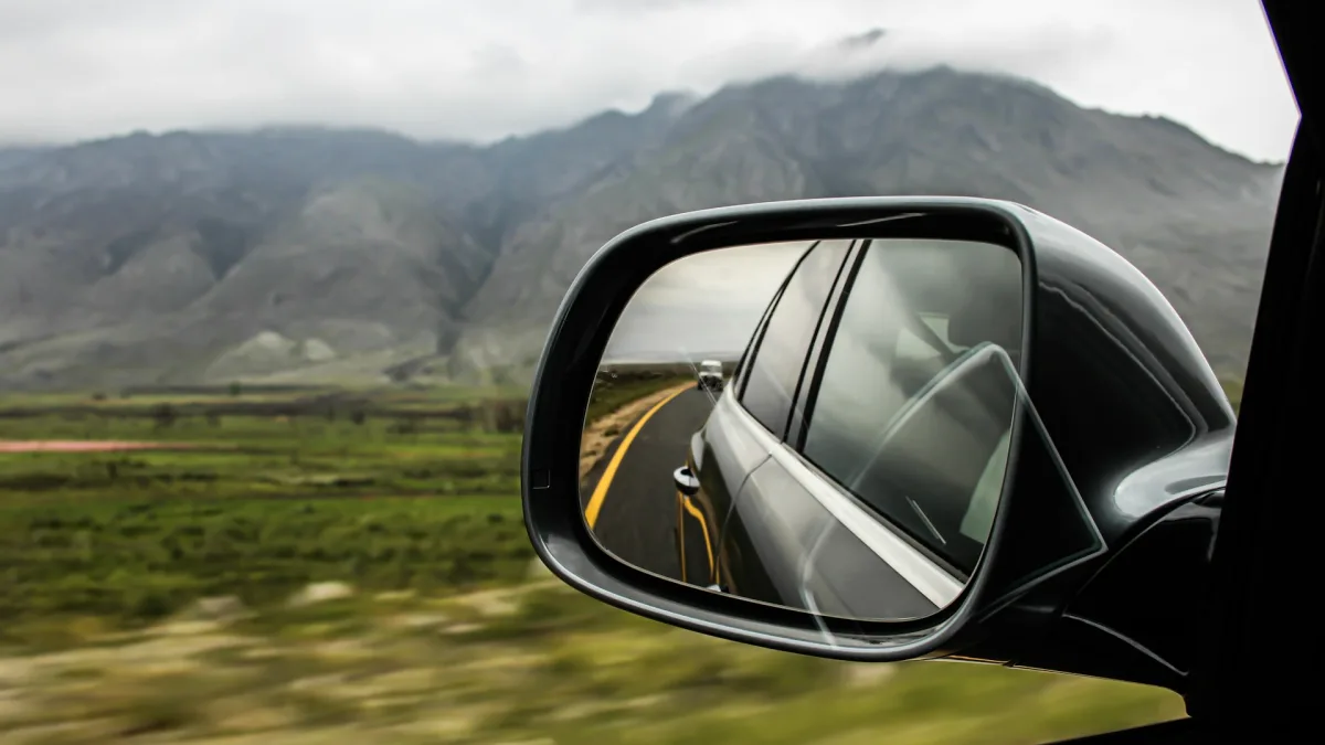 Forward ADAS camera housing mounted behind a rearview mirror on new windshield glass